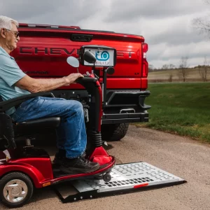 Picture of a man driving a mobility scooter onto a vehicle lift.