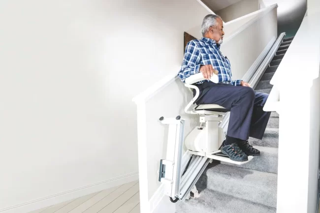 A man using a stairlift on the staircase in his home.