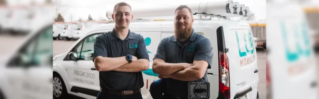 A picture of two LIO Mobility employees standing in front of their service van.