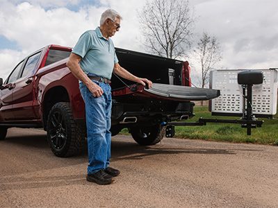 A man using the vehicle lift installed on the back of his truck.