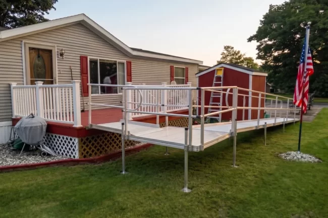 An aluminum modular wheelchair ramp installed onto the back deck of a home.