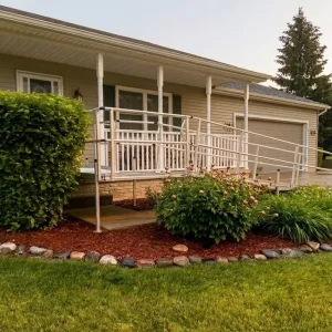 A different view of a wheelchair ramp installed off the driveway of a home.