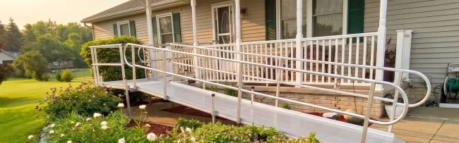 A home with a custom, L-shaped wheelchair ramp installed, going from the driveway to the front porch.