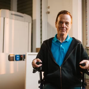Closeup of a man sitting in a rolling walker near a vertical platform lift.