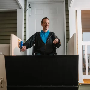 A man using a vertical platform lift to reach the entrance of his home.