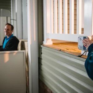 A picture of someone assisting a man using a vertical platform lift.